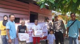 Keterangan foto : Personel Kepolisian membagikan bingkisan sosial kepada masyarakat yang berhak menerimanya.