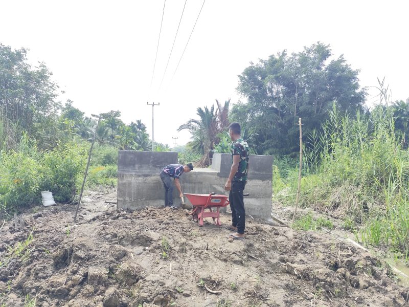 keterangan foto : Personel Koramil 01/Tembilahan bahu-membahu dengan masyarakat menuntaskan penimbunan material di sekitar pondasi angkur, bagian krusial dari pembangunan Jembatan Garuda yang berlokasi di Kelurahan Seberang Tembilahan Barat, Kecamatan Tembilahan, Kabupaten Indragiri Hilir.
