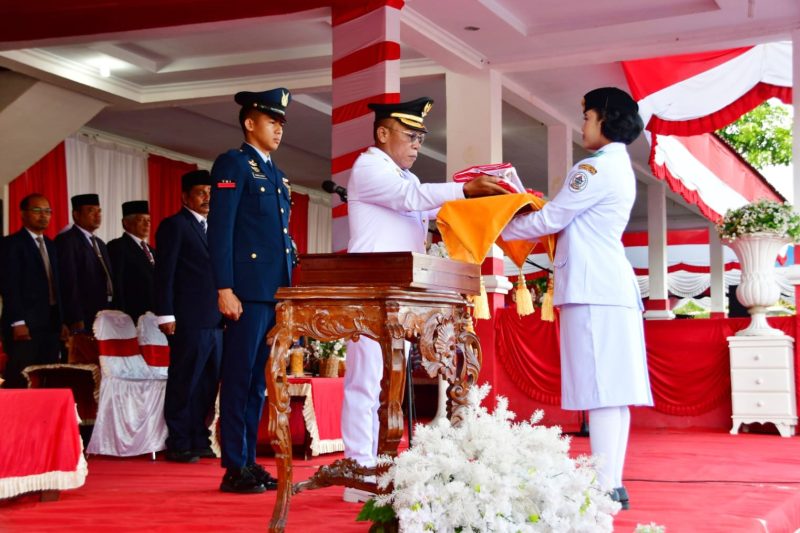 Keterangan Foto: Bupati Tapanuli Tengah, Masinton Pasaribu, menyerahkan Bendera Pusaka kepada Paskibraka Tapanuli Tengah dalam upacara peringatan HUT ke-81 RI di Lapangan GOR Pandan, Senin (17/8/2026).

-
