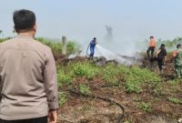 Keterangan Foto: Bhabinkamtibmas bersama Babinsa berupaya memadamkan api di lahan gambut yang terbakar di kawasan Jalan Labersa, Pekanbaru
