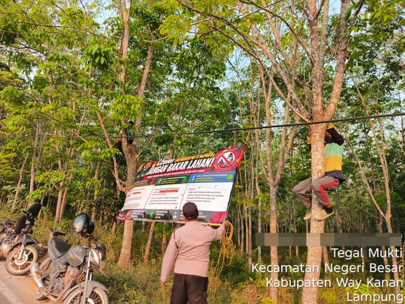 Keterangan Foto: Bhabinkamtibmas Polsek Negeri Besar sedang memasang banner imbauan larangan membakar lahan di kawasan perbatasan kebun Kampung Tegak Mukti dan Kampung Kaliawi Indah, Kecamatan Negeri Besar, Kabupaten Way Kanan. (Foto: Istimewa/Budi)