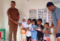 Ket. Foto : Pj Geuchik Andi Iskandar Rizza melalui Sekretaris Desa (Sekdes) Sarizal dan Ketua Tuha Peut Gampong Tgk.Mustafa menyerahkan Baju Seragam Polisi kepada Anak PAUD Bunda Cinta Raja (09/09/2025) 