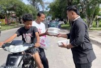 Ket. Foto : Ketua SAMMI Kota Langsa, Muhammad Reza, SH, Berbagi Jum'at Berkah, Kepada Masyarakat, yang melintas di depan Kantor Pegadaian Syariah Kota Langsa, Jum'at pagi (7 November 2025).