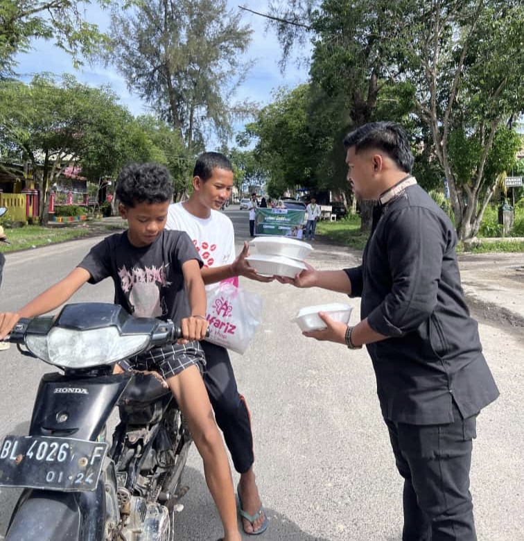 Ket. Foto : Ketua SAMMI Kota Langsa, Muhammad Reza, SH, Berbagi Jum'at Berkah, Kepada Masyarakat, yang melintas di depan Kantor Pegadaian Syariah Kota Langsa, Jum'at pagi (7 November 2025).