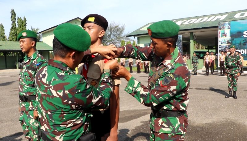 Keterangan foto : Personil Kodim 0104/Aceh Timur, Memasang Tanda Peserta kepada salah satu siswa peserta Perkemahan Sabtu Minggu (Persami) Korps Kadet Republik Indonesia (KKRI) Semester I Tahun Anggaran 2026.