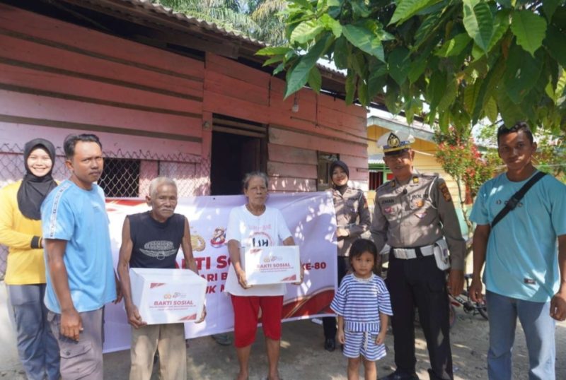 Keterangan foto : Personel Kepolisian membagikan bingkisan sosial kepada masyarakat yang berhak menerimanya.