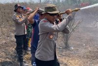 Keterangan Foto: Kapolres Way Kanan AKBP Ramadhona, S.H., S.I.K., saat melakukan penyemprotan air di lokasi titik api kebakaran hutan dan lahan.